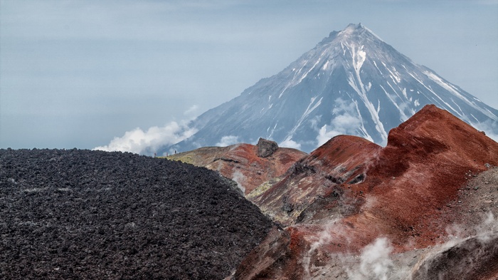 Volcanic landscape with snow-capped volcano and red hills