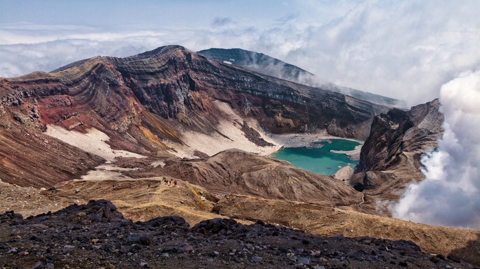 Volcanic crater with a turquoise lake and hikers