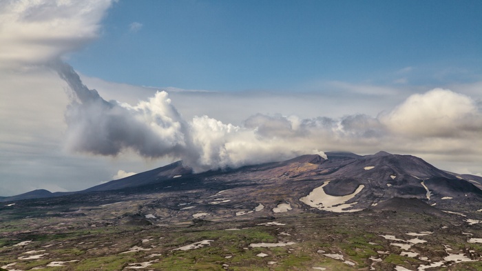 Volcano spewing smoke under a cloudy sky