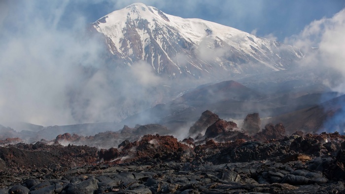 Volcano with snow-capped peak and lava field