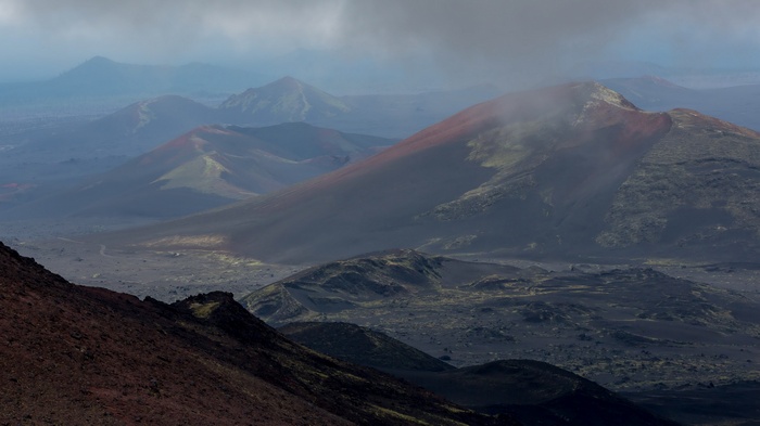 Volcanic landscape with red-capped mountains and clouds