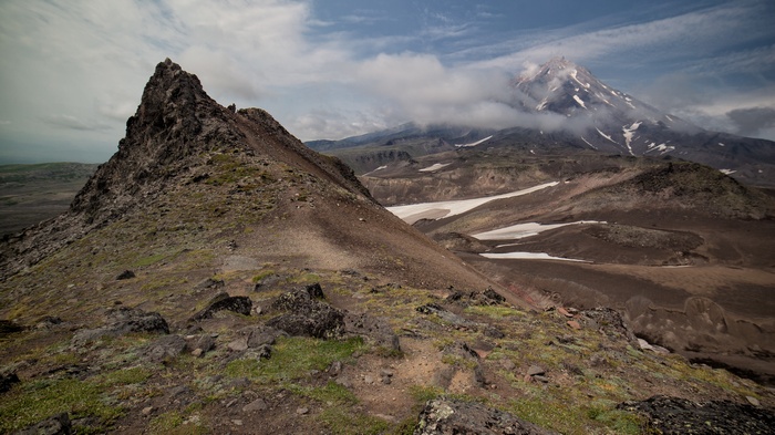 Volcanic landscape with a sharp peak and a distant volcano