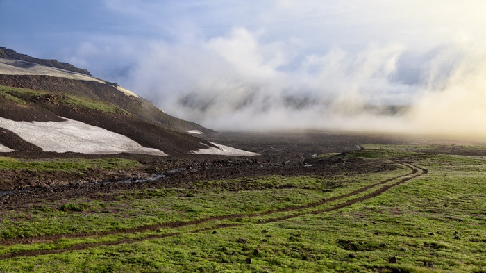 Mountainous landscape with snow patches and fog