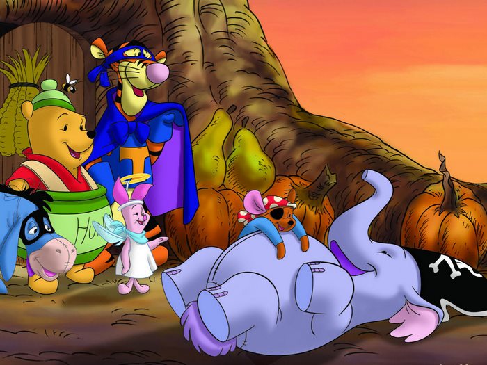 Winnie the Pooh characters in costumes with pumpkins