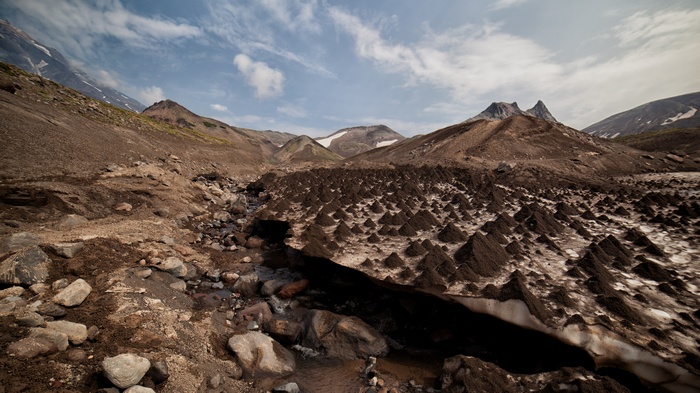 Volcanic landscape with snow-capped mountains and a stream