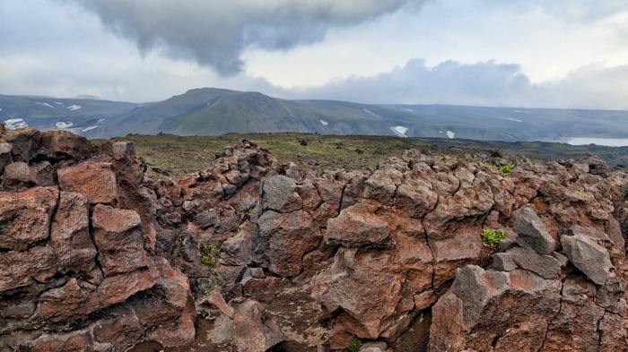 Rocky volcanic landscape with distant mountains and clouds