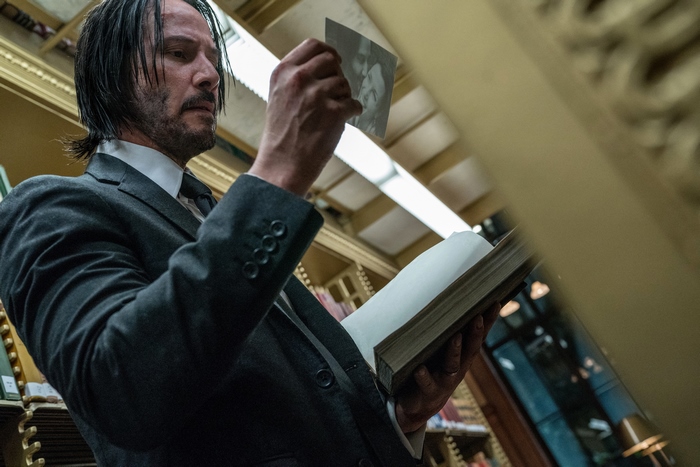 John Wick holding a photo and a book