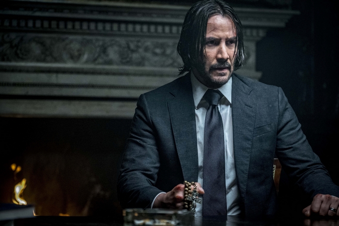 John Wick in a Suit Holding Rosary Beads
