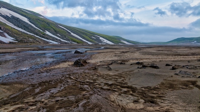 Barren landscape with snow-capped mountains and cloudy sky