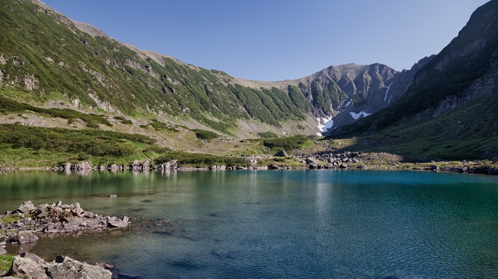 Mountain lake with rocky shores and green slopes