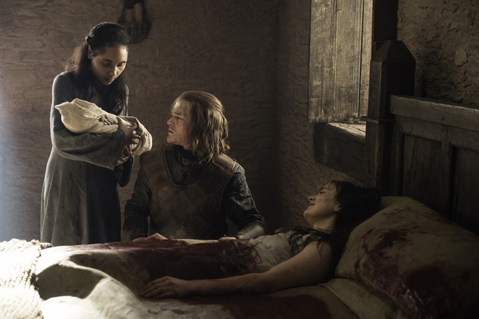 Woman holding baby with man and woman in bed