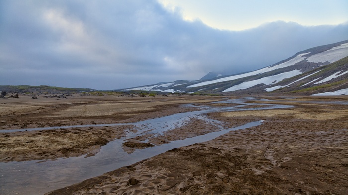 Mountain landscape with snow patches and a stream