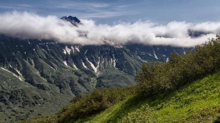 Mountain range with clouds and green slopes