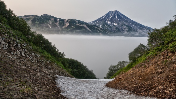 Volcanoes shrouded in mist with snow patches
