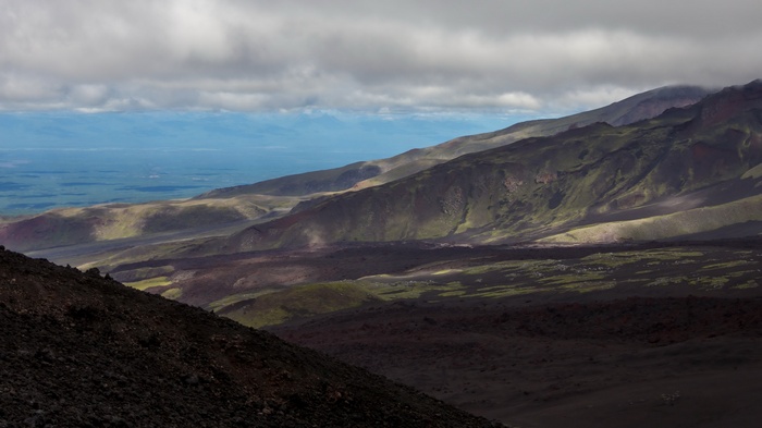 Volcanic landscape with distant ocean and clouds