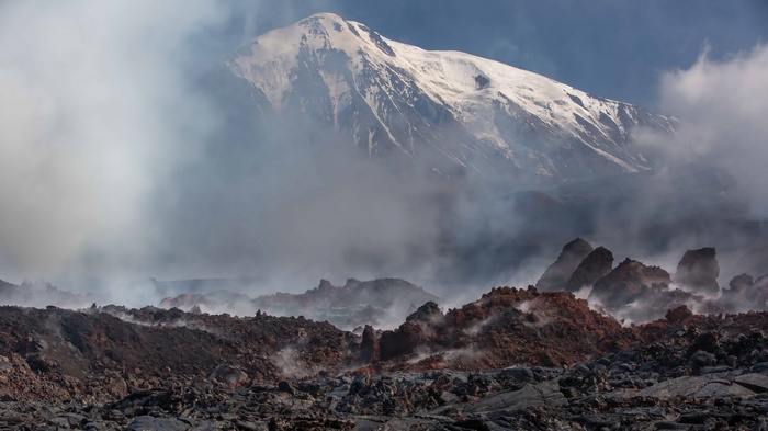 Volcanic landscape with snow-capped mountain and steam