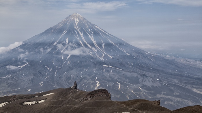 Volcano with smoke and rocky foreground