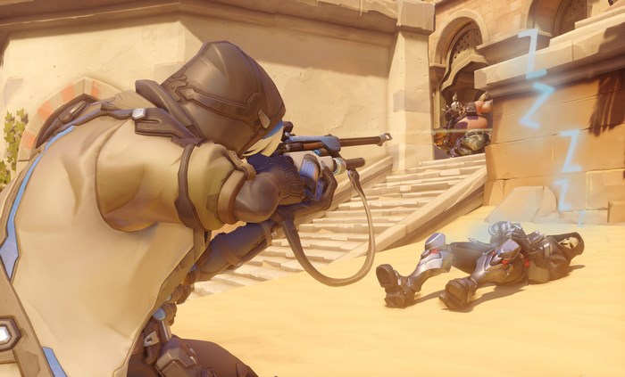 Ana from Overwatch aiming a rifle at a downed opponent
