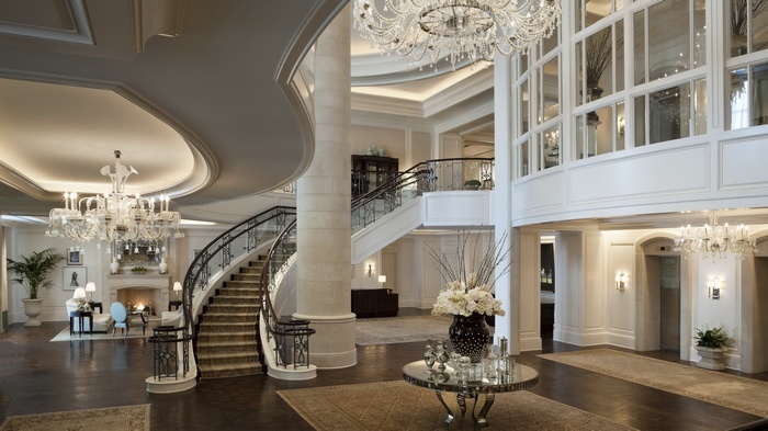 Grand hotel lobby with a sweeping staircase and chandeliers