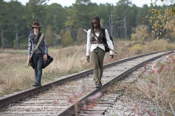 Michonne and Carl walking on train tracks