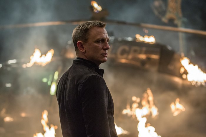 James Bond in front of a burning helicopter