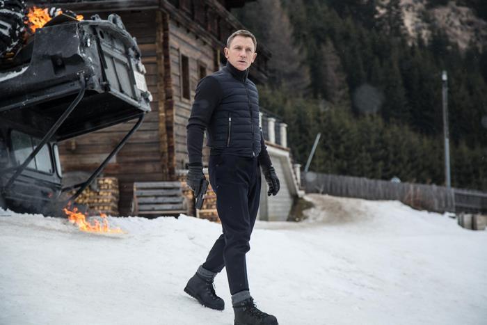 James Bond in snowy mountains with burning vehicle
