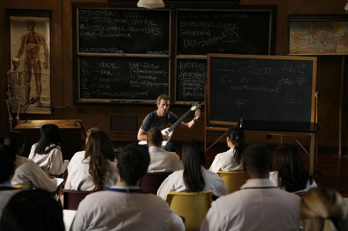 Hugh Laurie as Gregory House playing guitar in classroom