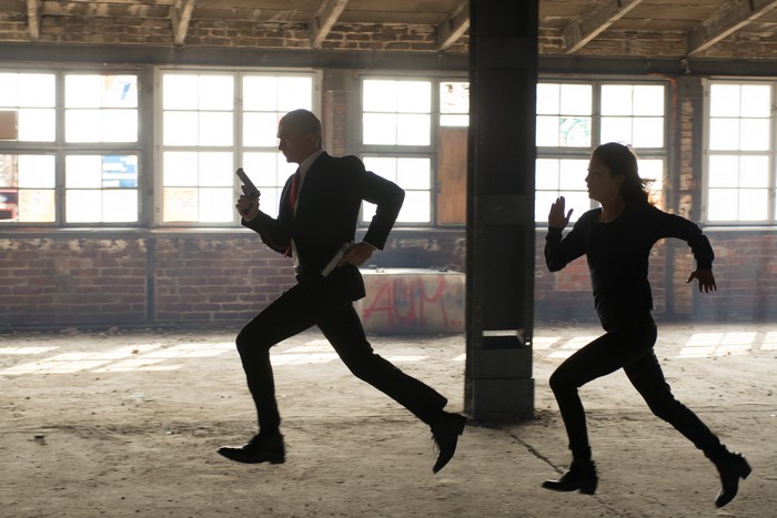 Agent 47 running with a gun