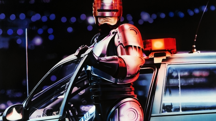 RoboCop leaning on a police car at night