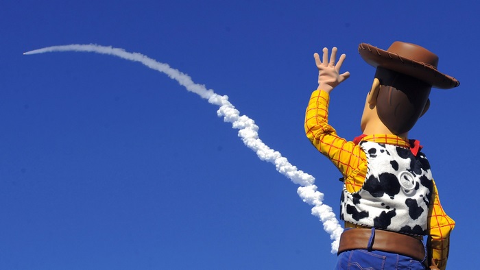 Woody from Toy Story waving at a rocket launch