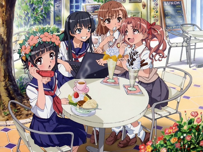 Four girls at a cafe with desserts and a laptop