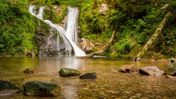 Waterfall cascading into a clear pool with rocks