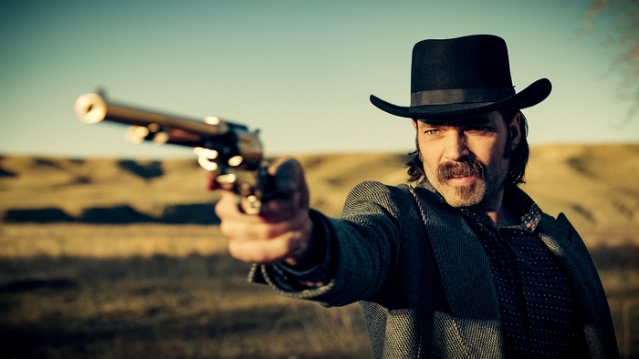 Man in cowboy hat aiming a gun