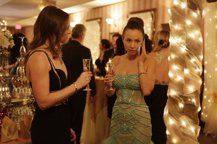 Woman in a teal dress talking on a phone at a party