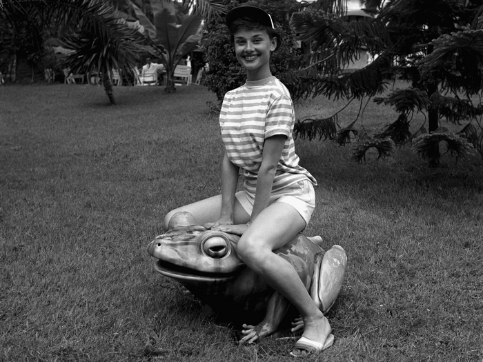 Audrey Hepburn sitting on a frog statue