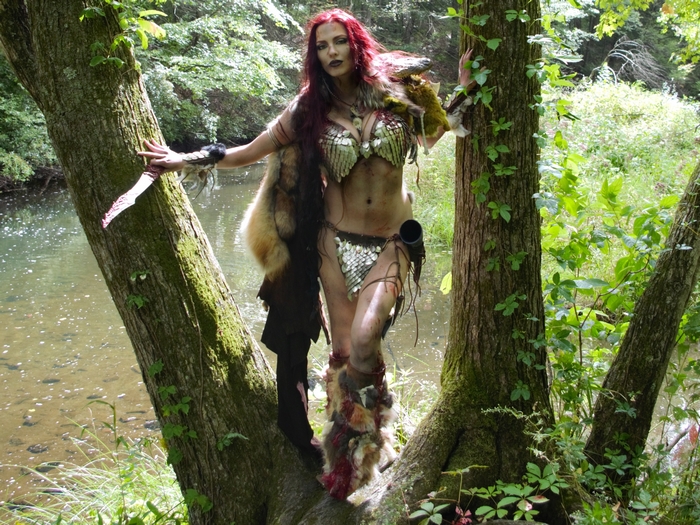 Red Sonja in a forest by a stream