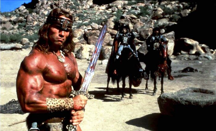 Conan the Barbarian with sword and warriors on horseback