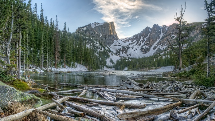 Rocky Mountains Lake with Snow-Capped Peaks and Driftwood