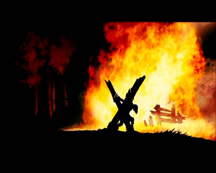 Jonah Hex carrying the cross in front of a fire
