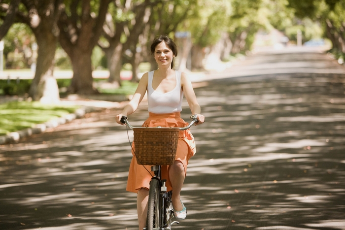 Woman riding a bicycle on a tree-lined street