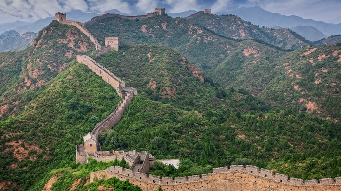 The Great Wall of China winding through green mountains