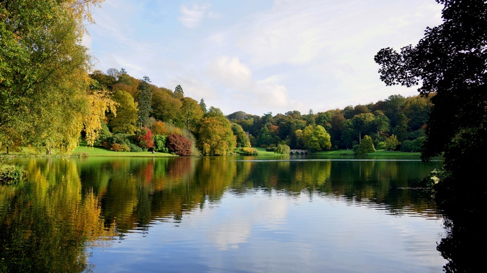 Autumn trees reflected in a lake with a stone bridge