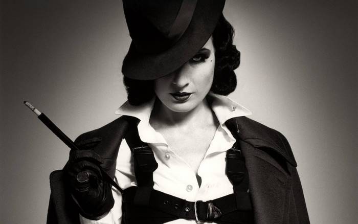 Dita Von Teese in a hat holding a cigarette holder
