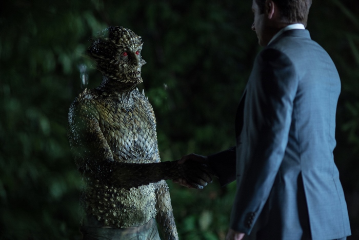 Reptilian creature and man shaking hands