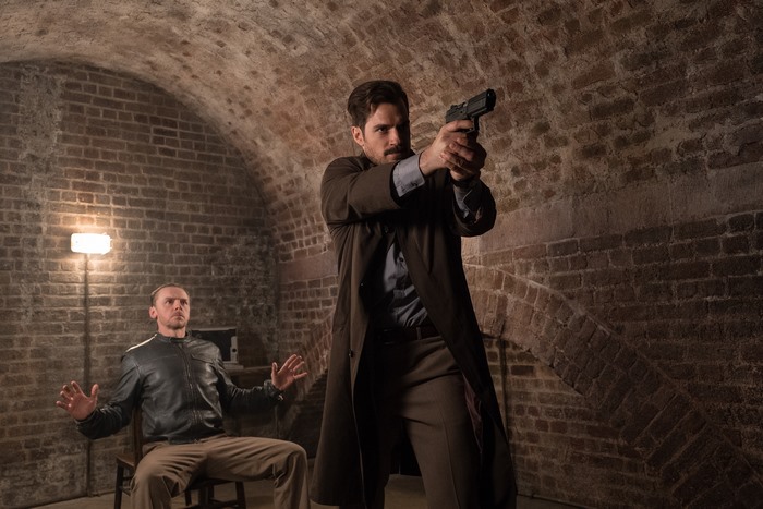 August Walker holding a gun in a brick room