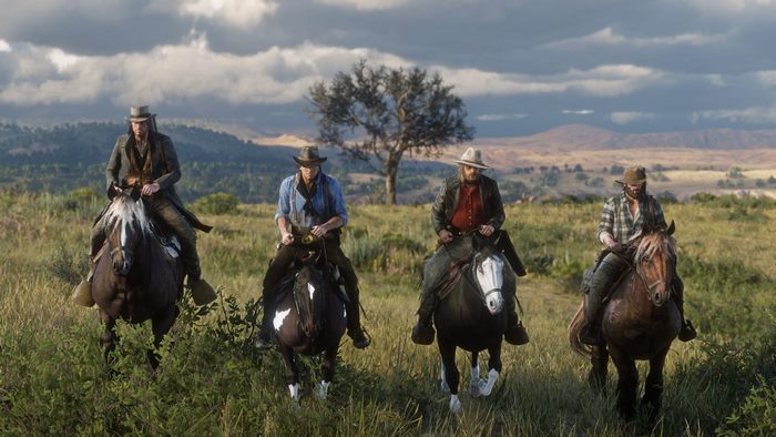 Four men on horseback in a grassy field