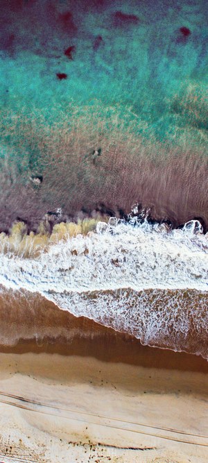 Drone view of ocean waves crashing on a sandy beach