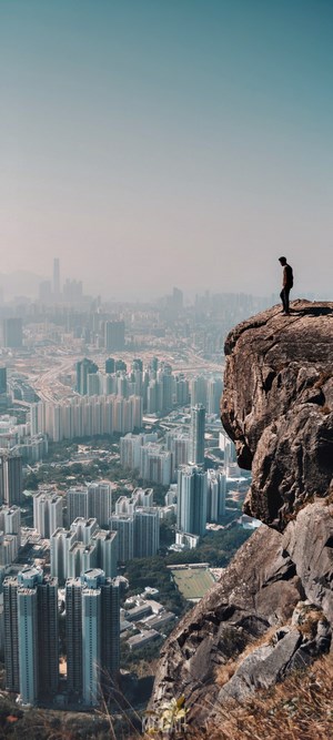 Man standing on a cliff overlooking a city