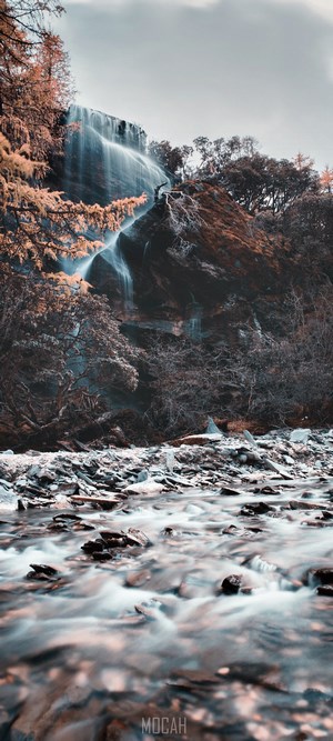 Waterfall flowing over rocks with a river in the foreground