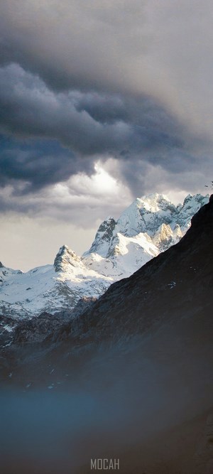 Snow-capped mountains under stormy clouds